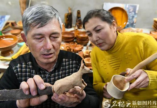 12月1日，艾尼江在工作室和妻子一起制作木雕作品。