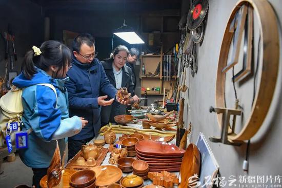 12月1日，游客在艾尼江的工作室选购木雕作品。