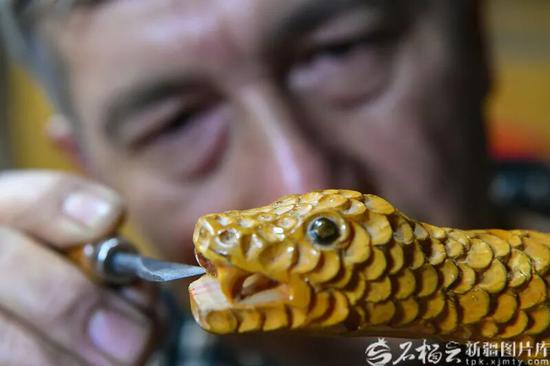 一段木头在艾尼江的精雕细琢下，似乎有了生命（12月1日摄）。