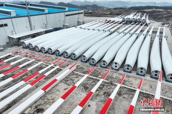 12月11日，在贵州省龙里县的一家复合材料科技生产企业车间内，工人加紧生产风电叶片，以满足市场订单需求。近年来，龙里县将新能源产业创新发展作为重要方向，在政策支持与服务保障的双重助力下，该县风电叶片产业订单足销售旺，成为推动地方经济发展的强劲引擎。图为待出厂的风电叶片。（无人机照片）记者 瞿宏伦 摄