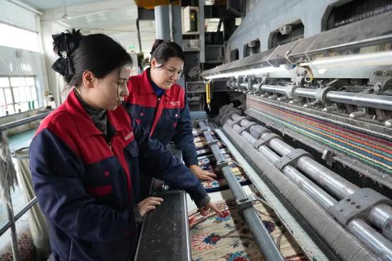 宇宙地毯有限公司车间，工作人员查看地毯编织情况。努尔古再丽 摄