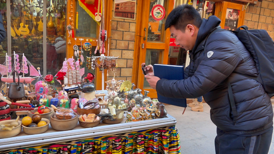 游客用手机拍摄各类非遗文创产品。努尔古再丽 摄