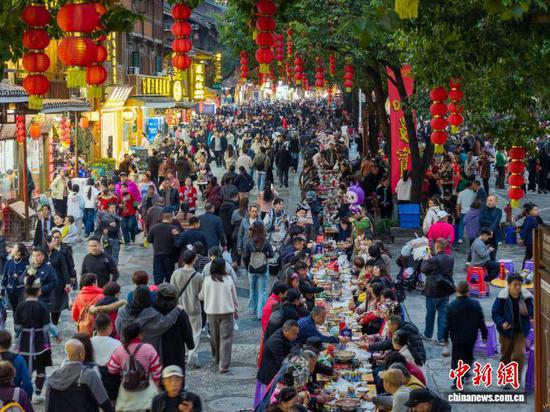 12月20日，贵州省黎平县肇兴侗寨，游客在吃长桌宴。龙建睿 摄