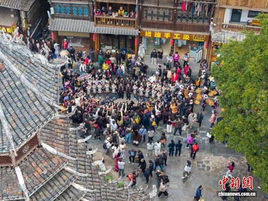 12月20日，贵州省黎平县肇兴侗寨，侗族青年为游客唱侗歌。龙建睿 摄