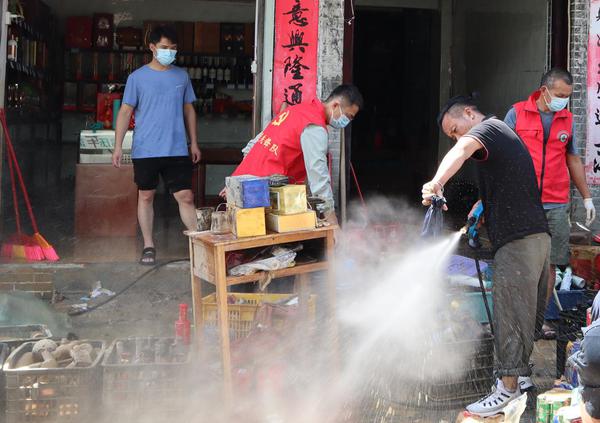 图为百色烟草员工帮助清洗店内商品。周世伟 摄