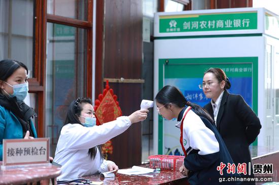 工作人员正在给适龄女孩测量体温。张美摄