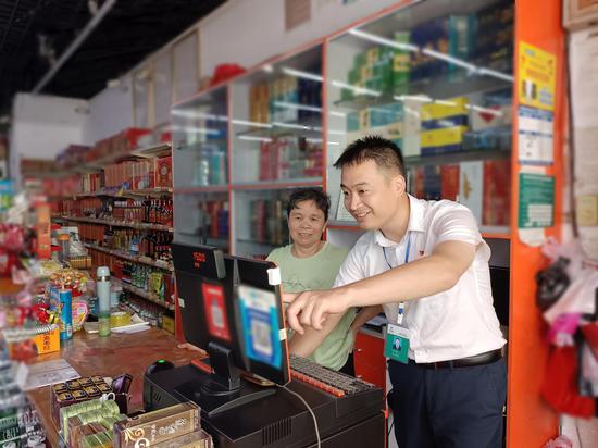 图为烟草客户经理为零售户检修终端销售系统。 陈志连 摄
