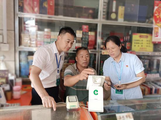 图为烟草客户经理指导老年人运用销售终端系统。覃仕隆 摄