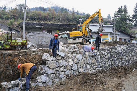 在仁怀市五马镇屯山村错车道项目建设现场，村民和机械设备有条不紊地施工作业。