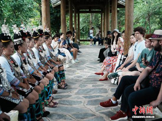 2025年夏天，游客在贵州省黎平县黄岗侗寨听村民唱侗族大歌。记者 周燕玲 摄