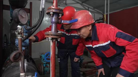 在阜康市西树窝子2号换热站内，工作人员对换热站压力、温度、流量进行检查，观看运行数据是否正常。张鹏 摄
