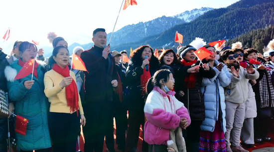 本土歌手阿里木与现场游客齐声高唱《我和我的祖国》，手中的红旗随之舞动。杨涛 摄3