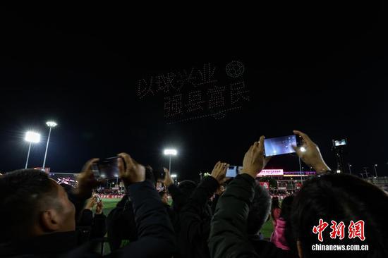 1月1日晚，贵州省黔东南苗族侗族自治州榕江县元旦专场无人机编队表演、烟花秀在“村超”球场上演。图为民众在拍摄无人机编队呈现的“以球兴业，强县富民”。