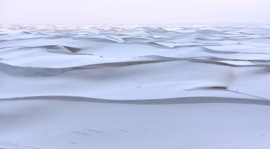 皑皑白雪覆盖广袤沙海。阿巴拜科日摄