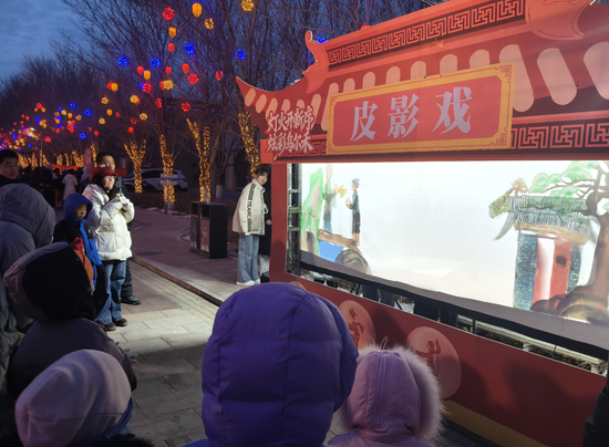 1月1日晚，市民在乌尔禾度假区上海街中段观赏非遗项目皮影戏。克拉玛依融媒记者 李利利 摄