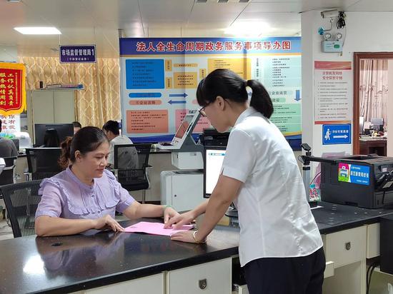 图为证件管理员向群众介绍“一页知晓”宣传单。陈志阳 摄