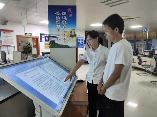 图为证件管理员覃英涛耐心为群众讲解政策文件。陈志阳 摄
