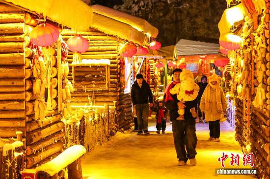 1月7日晚，游客在贵州省六盘水市钟山区“南国雪乡”项目内游览。该项目由钟山区梅花山旅游景区凭借梅花山滑雪场的核心优势，以“厚雪压木屋、红灯映炊烟”为设计理念打造，旨在让南方游客无需北上即可邂逅地道雪乡风情，打造沉浸式文旅新体验。