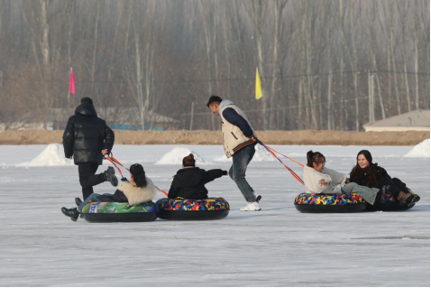 烏什縣阿克托海鎮(zhèn)阿克博孜村滑冰場(chǎng)，游客在體驗(yàn)雪圈、拉爬犁等運(yùn)動(dòng)項(xiàng)目。