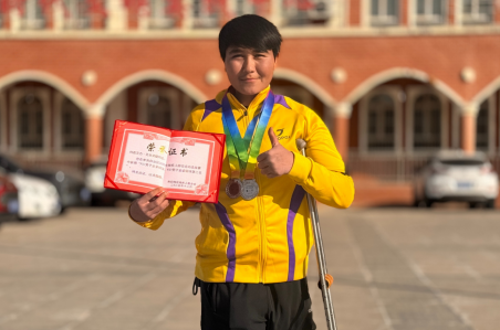 肉孜艾力·艾合買(mǎi)提胸前掛著兩枚銀牌、手中緊握榮譽(yù)證書(shū)，目光堅(jiān)定地望向鏡頭，盡顯拼搏后的榮耀與自信。