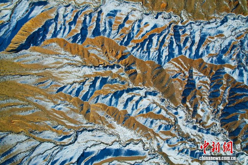 新疆溫宿：丹霞山巒裹殘雪 金黃肌理與素白雪痕相映