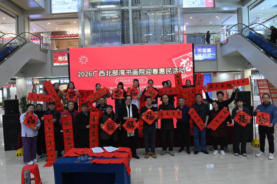 图为书画家与获得春联的民众合影。记者 蒋雪林 摄