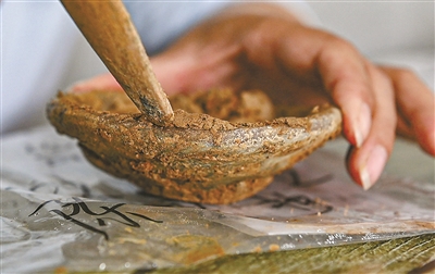 考古工作人员清理刚出土的文物。记者 张之冰 摄