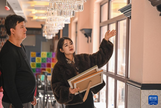 在新疆墨玉县普恰克其镇，穆耶赛尔·艾合麦提托合提（右）为一家即将开业的桑皮纸主题餐厅设计桑皮纸元素软装（1月12日摄）。