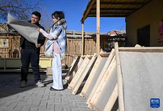 在新疆墨玉县桑皮纸产业园，穆耶赛尔·艾合麦提托合提（右）和桑皮纸制作技艺县级代表性传承人比拉力·图尔荪巴柯交流（1月14日摄）。