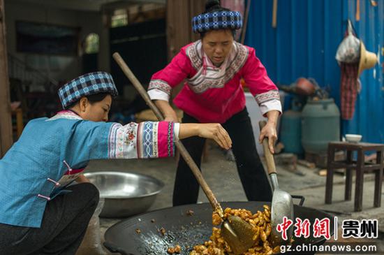 将米团和红糖浆混合，同时撒入提前制作好的芝麻和酥麻。张帆 摄
