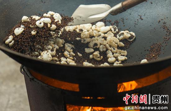 搅拌江砂炒制萢果，使其加热膨胀。张帆 摄