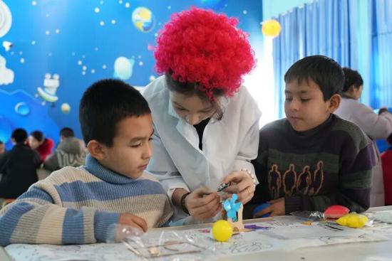 科技馆工作人员指导学生制作卫星模型。努尔古再丽 摄