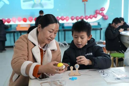 家长与孩子一起动手制作模型。努尔古再丽 摄