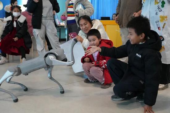 孩子开心地与机器狗互动。努尔古再丽 摄