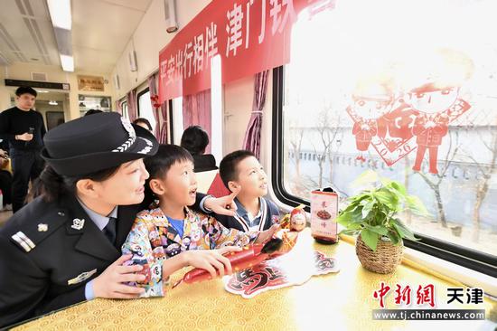 图为北京铁路公安局天津公安处乘警支队民警登乘列车为旅客送上温馨祝福。（北京铁路公安局天津公安处供图）