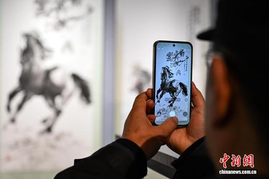 图为参观者在拍摄展出的水墨奔马画作品。中新社记者 瞿宏伦 摄