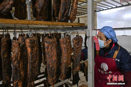 2月5日，一位工作人员在查看腊肉熏烤情况。中新社记者 瞿宏伦 摄