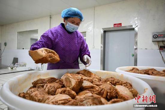 2月5日，一位工作人员在整理腌制的腊肉。中新社记者 瞿宏伦 摄