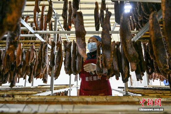 2月5日，一位工作人员在摆放熏烤好的腊肉。中新社记者 瞿宏伦 摄