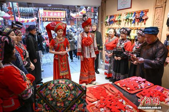 2月5日，在贵州省黔南州都匀市石板街举行的一场布依族婚俗展演，吸引不少民众观看。展演现场热闹非凡，迎亲队伍身着布依族盛装在欢快的芦笙曲中沿着石板街巡游，民众不仅可以观看婚俗仪式，还能参与对情歌、抛绣球等环节。图为布依族婚俗展演现场。瞿宏伦 摄