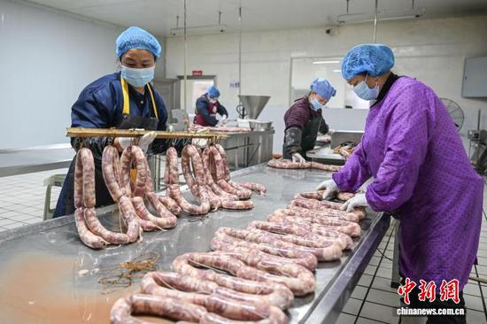2月5日，工作人员在罐装腊香肠。中新社记者 瞿宏伦 摄