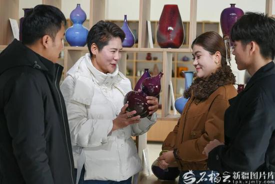2月8日，新疆昆仑玉瓷科技文化有限公司负责人连文娟（左二）为顾客介绍玉瓷产品。