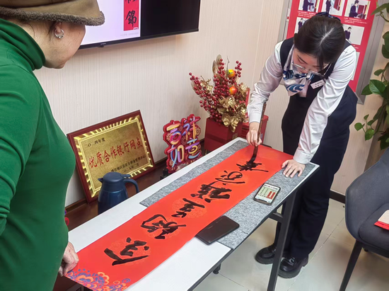 喀什分行克孜勒都维路支行工作人员为客户书写春联（来源：乌鲁木齐银行）