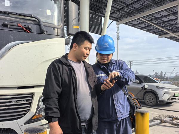 工作人员在给新能源重卡司机讲解充电指南。梁敏 摄 工作人员在给新能源重卡司机讲解充电指南。梁敏 摄