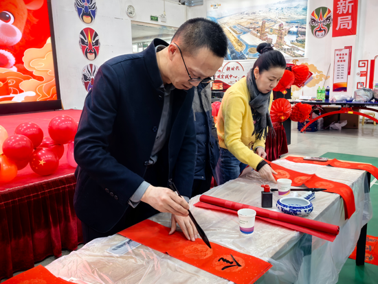 市文化馆副研究馆员刘永强与志愿者们现场挥毫泼墨，书写春联。郑家爽 摄