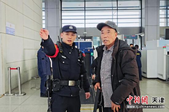 图为天津铁路公安处民警抬手为身旁的旅客指引方向。用细致服务温暖了旅客的春运旅途,让返乡之路更安心顺畅。(北京铁路公安局天津公安处供图)