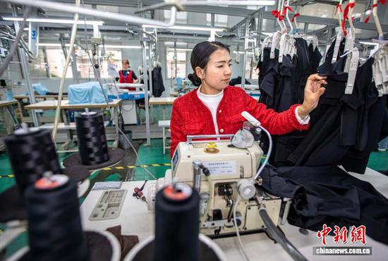 图为2月24日,工人在贵州省黔西市经济开发区一家服饰企业车间生产线上加工服饰。史开心 摄 图为2月24日,工人在贵州省黔西市经济开发区一家服饰企业车间生产线上加工服饰。史开心 摄