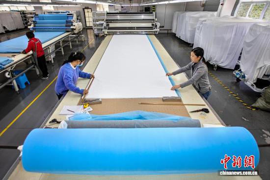 图为2月24日,工人在贵州省黔西市经济开发区一家服饰企业车间裁床上拉布。史开心 摄 图为2月24日,工人在贵州省黔西市经济开发区一家服饰企业车间裁床上拉布。史开心 摄