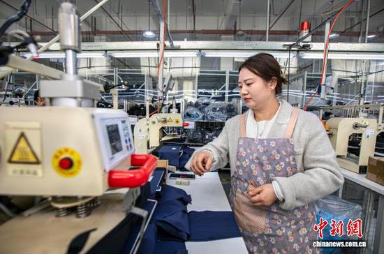 图为2月24日,工人在贵州省黔西市经济开发区一家服饰企业车间烫压服饰标签。史开心 摄 图为2月24日,工人在贵州省黔西市经济开发区一家服饰企业车间烫压服饰标签。史开心 摄