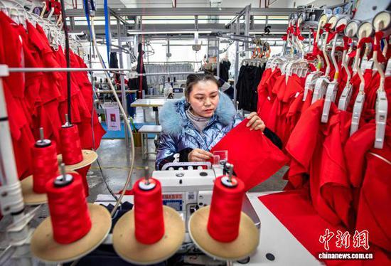 图为2月24日,工人在贵州省黔西市经济开发区一家服饰企业车间生产线上加工服饰。史开心 摄 图为2月24日,工人在贵州省黔西市经济开发区一家服饰企业车间生产线上加工服饰。史开心 摄